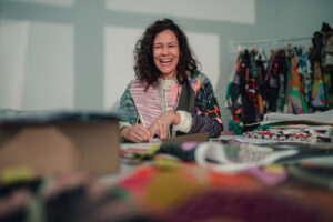 Vrouw lachend in de camera tijdens haar werk in de textiel